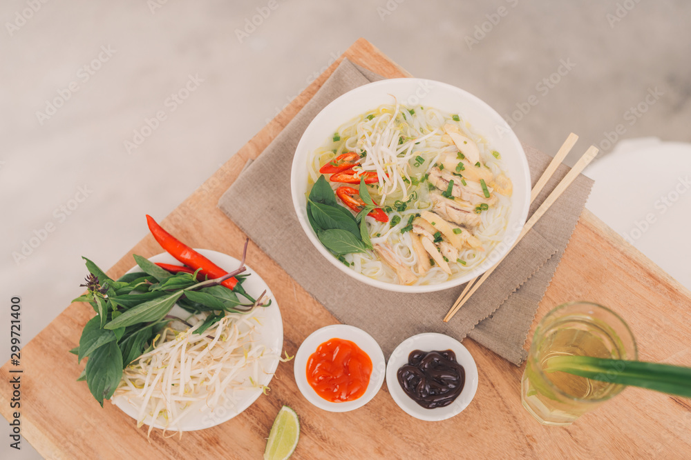 Pho Bo - Vietnamese fresh rice noodle soup with beef, herbs and chili. Stock being poured. Vietnams