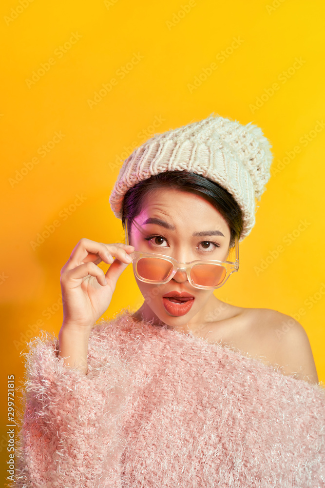 Emotional asian girl with colorful makeup posing on yellow background with eyeglasses. Indoor photo 