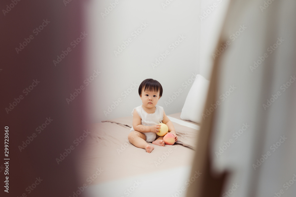 Funny happy toddler girl playing with toy on bed. Kids play at home.