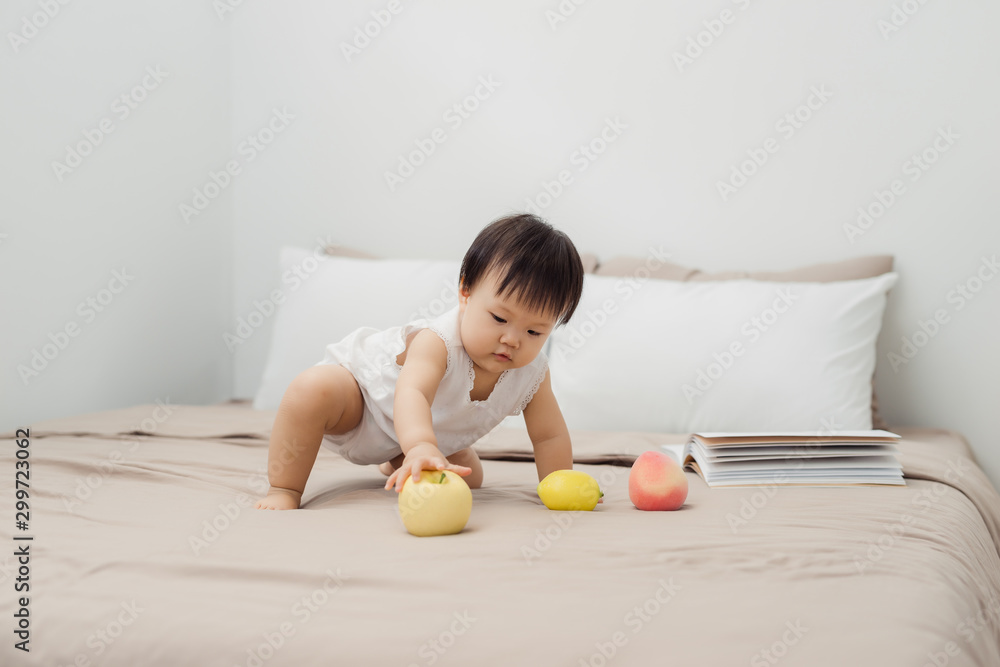 Cute baby playing with toy on bed. Kid playing at home