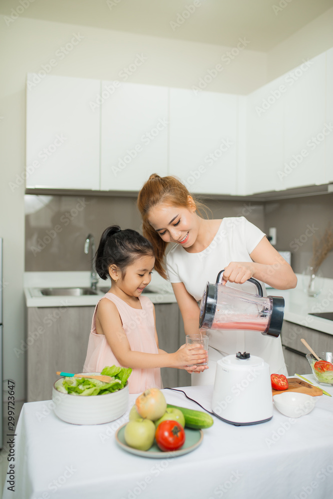 Mother and Daughter are preparing the salad in blender Menu tasty smoothie and ingredients on table 