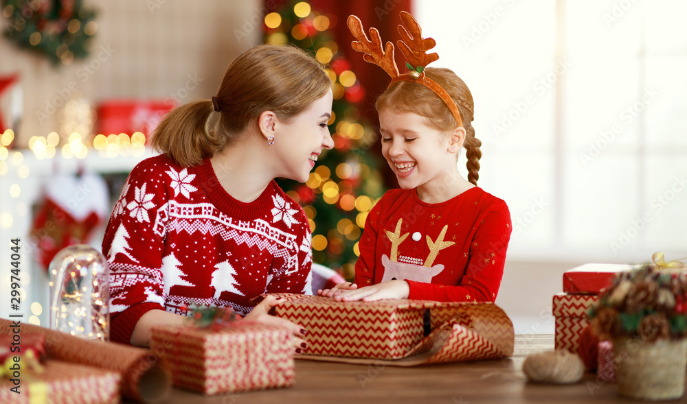 happy family mother and child pack Christmas gifts at home near Christmas tree.