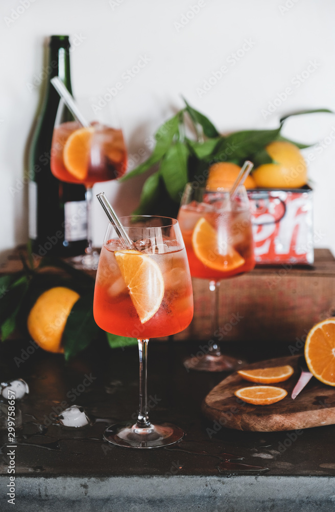 Aperol Spritz aperitif alcohol cold drink in glasses with straws with oranges and ice cubes on concr