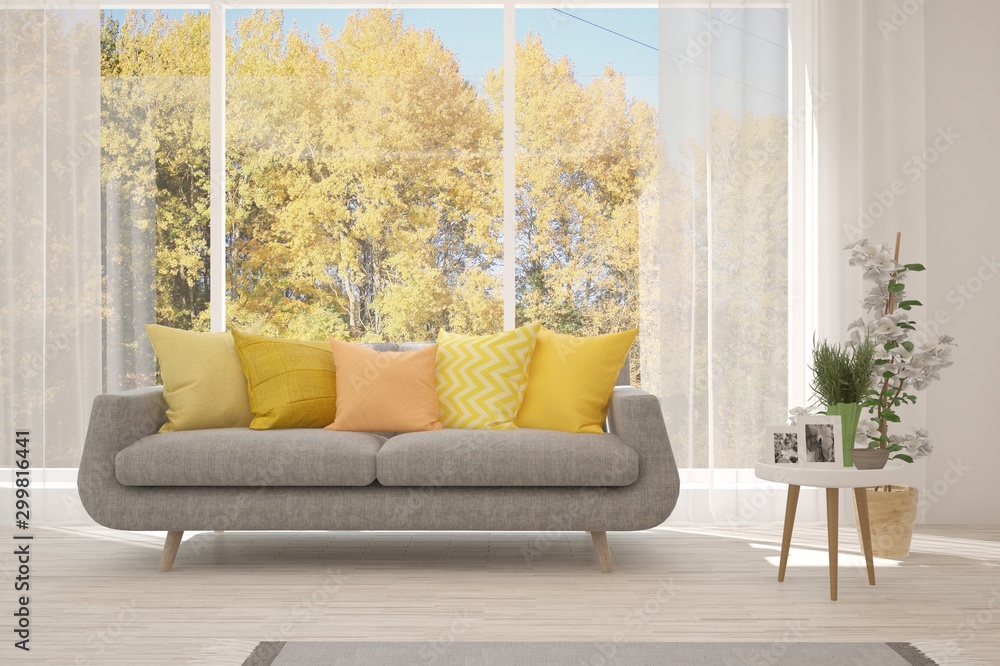 Stylish room in white color with sofa and autumn landscape in window. Scandinavian interior design. 