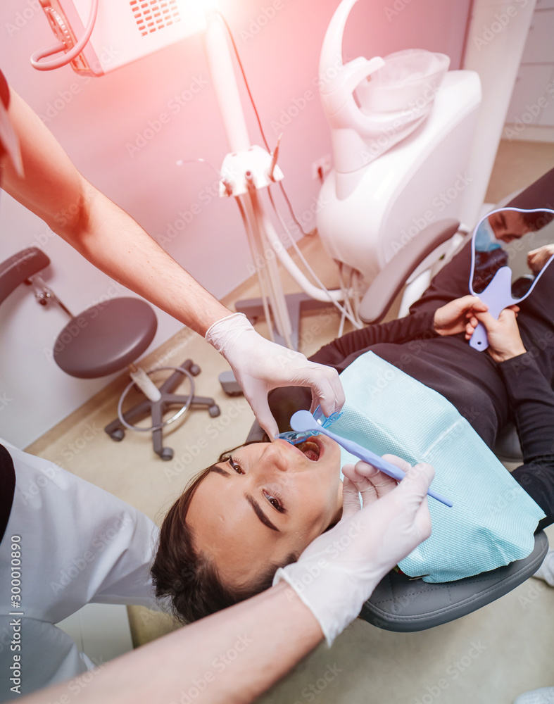 Dentist is treating female patients teeth at stomatology chair. View from the top. Teeth health con