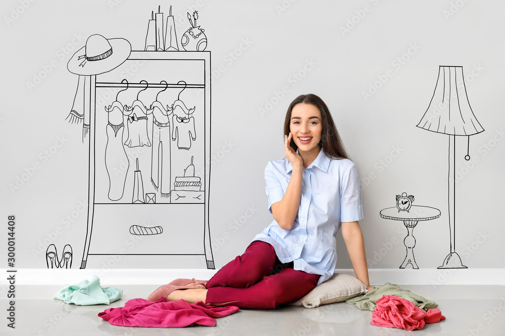 Young woman with stylish clothes imagining interior of dressing room