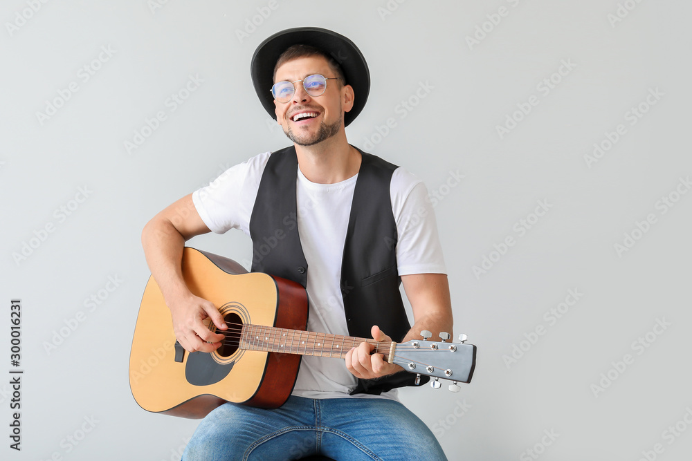 Handsome man playing guitar on light background