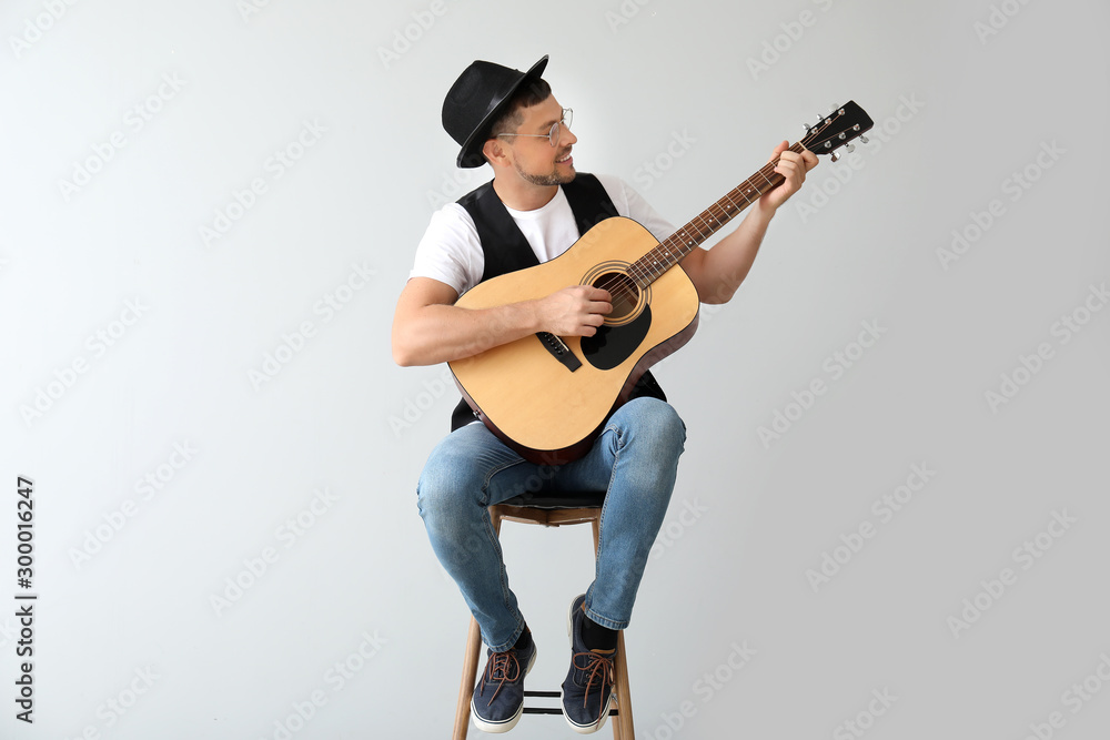 Handsome man playing guitar on light background