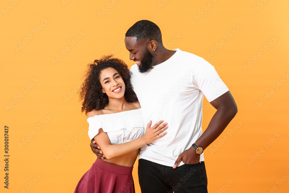 Portrait of happy African-American couple on color background