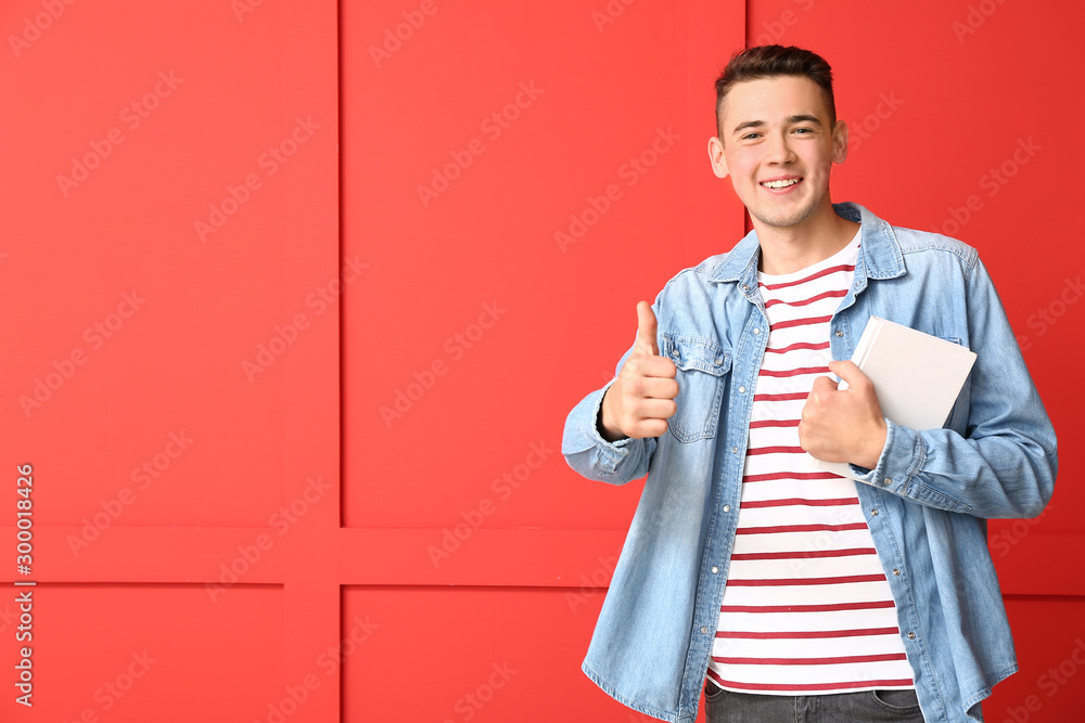 Cool teenage schoolboy showing thumb-up on color background