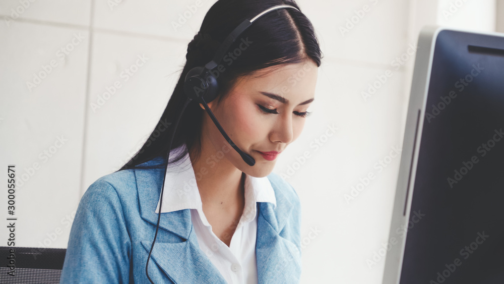 Customer support agent or call center with headset works on desktop computer while supporting the cu