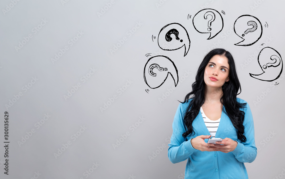 Question marks with speech bubbles with thoughtful young woman holding a smartphone