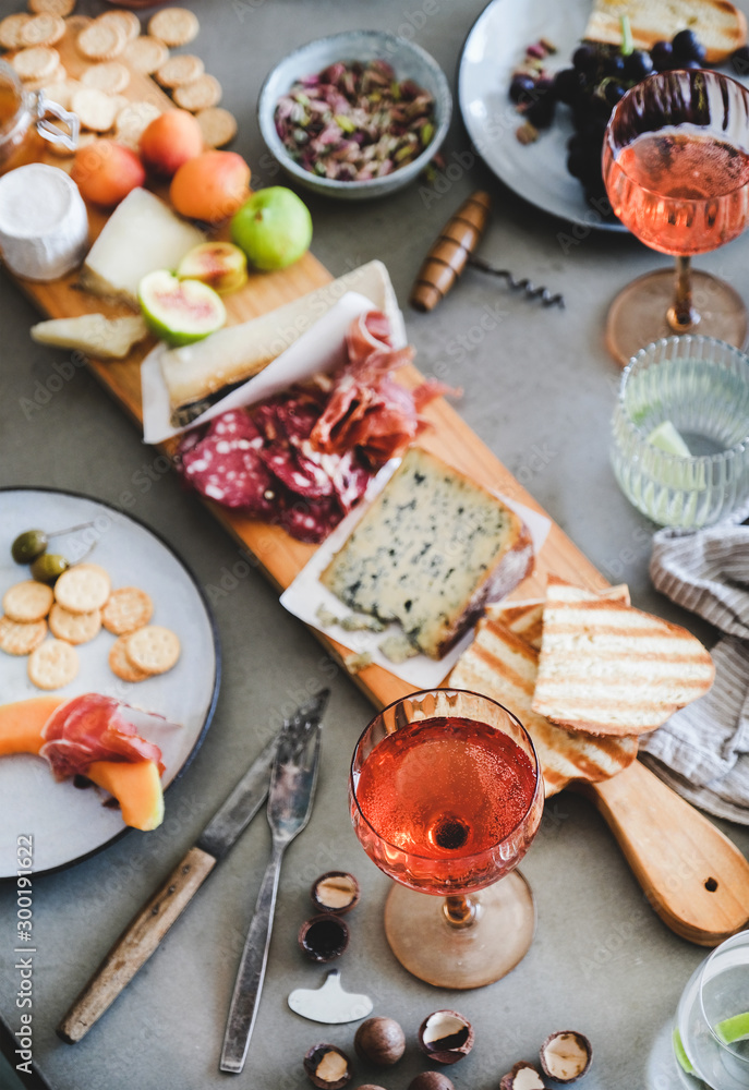 Mid-summer picnic with wine and snacks. Charcuterie and cheese board, rose wine, nuts, olives and fr