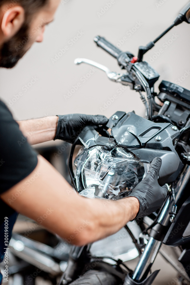 Worker repairing motorcycle headlight in the workshop