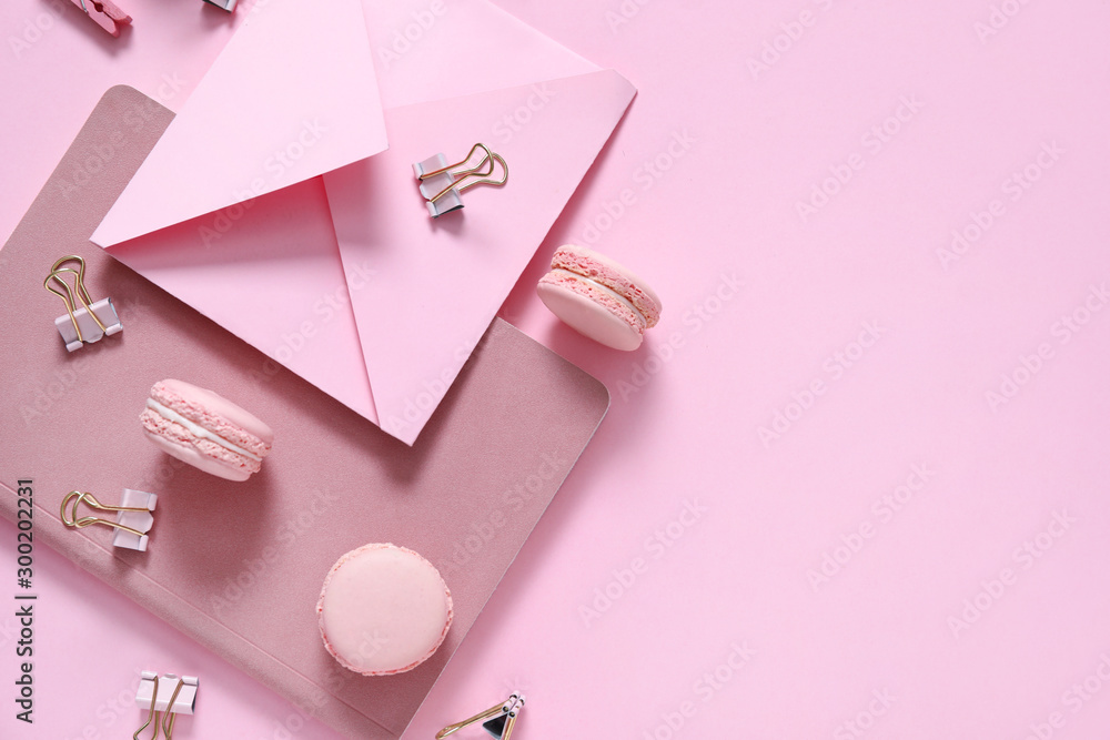 Tasty macarons with stationery on color background