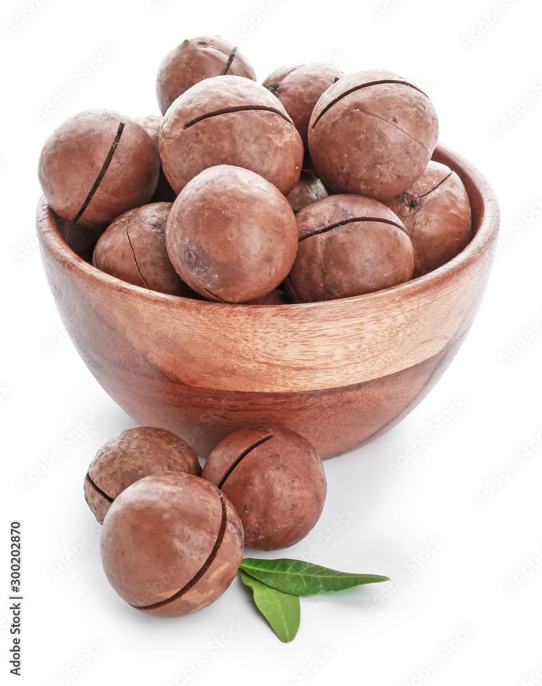 Bowl with tasty macadamia nuts on white background