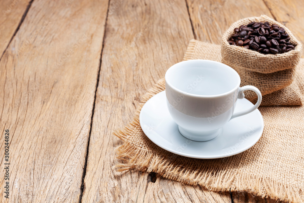 Empty white coffee cup with coffee beans on wooden plank floor background