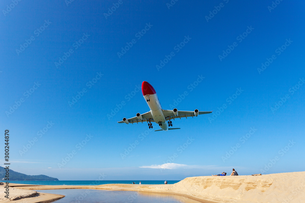 Commercial airplane landing above sea and clear blue sky over beautiful scenery nature background lo