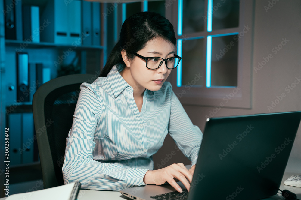 Young asian chinese woman working on laptop in office in late night. elegant businesswoman overtime 