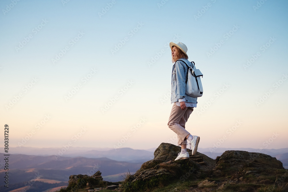 背着背包在山上徒步旅行。日落时，年轻女孩在山上行走。山