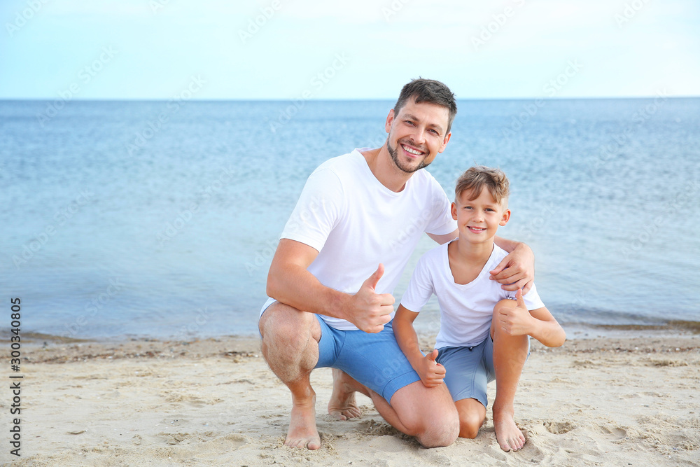 Portrait of happy father and son on sea beach