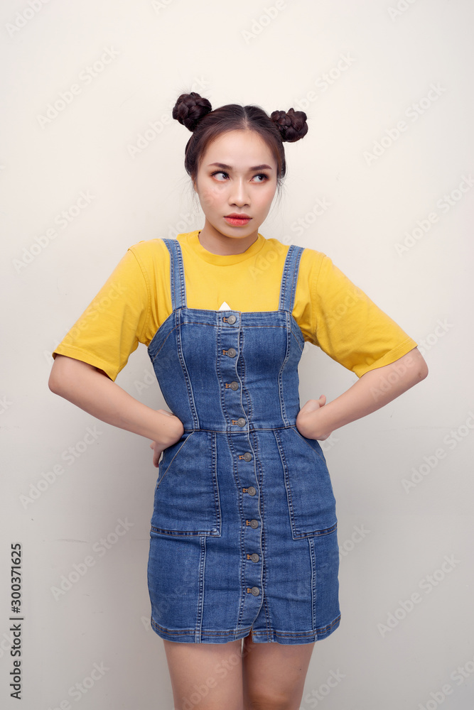 Portrait of grimacing offended young gorgeous woman model with hands on waist and bun hairstyle isol