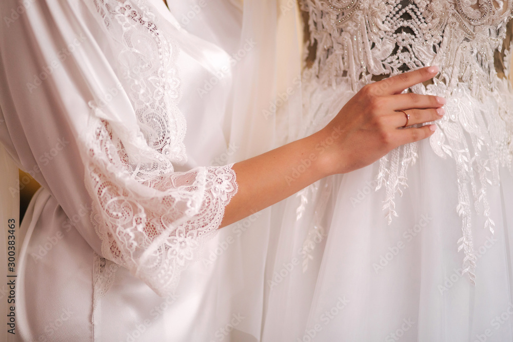 Beautiful bride stand by wedding dress in the morning