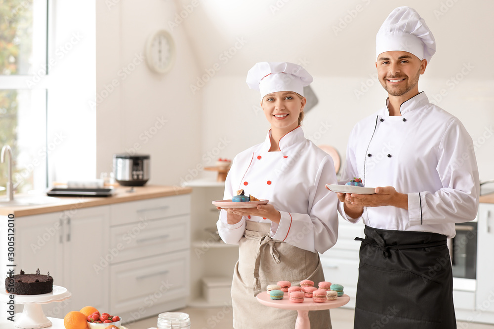 Young confectioners with tasty desserts in kitchen