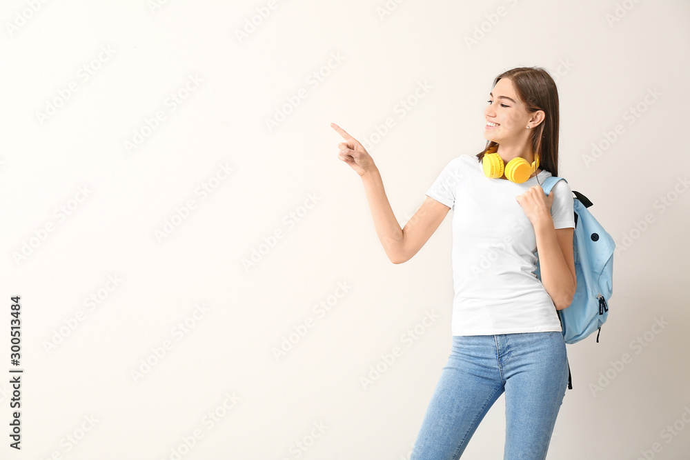 Beautiful female student pointing at something on white background