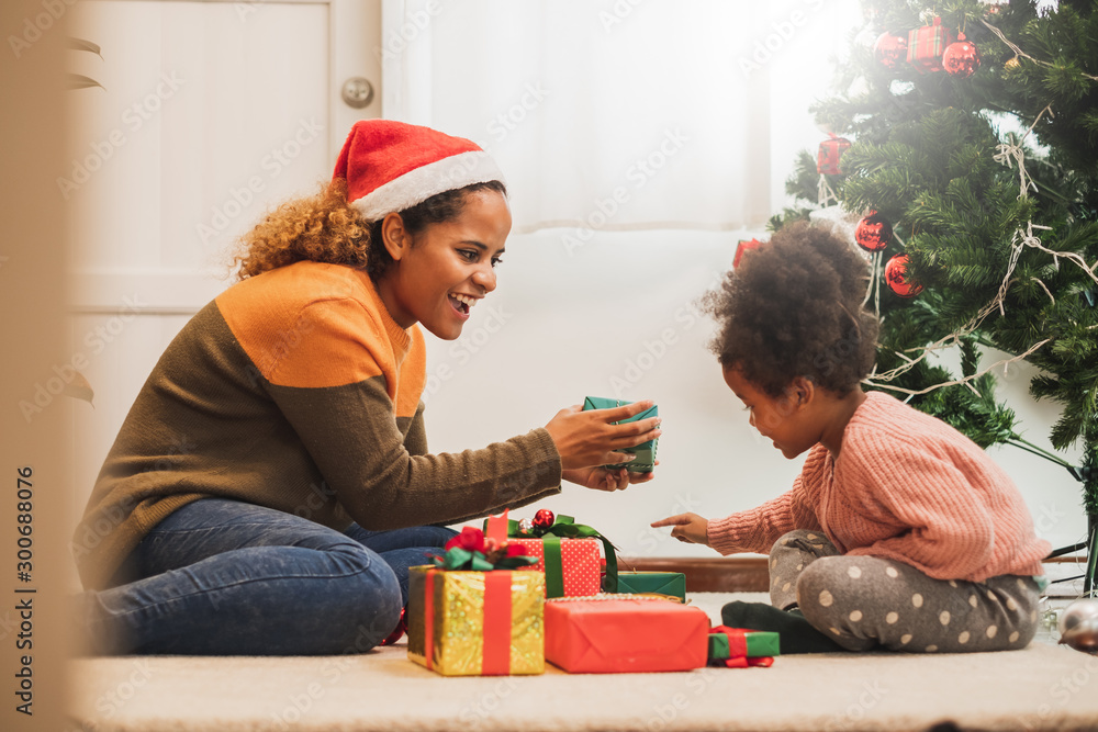 Young black african mother giving Christmas present gift box to her daughter, merry christmas and ha