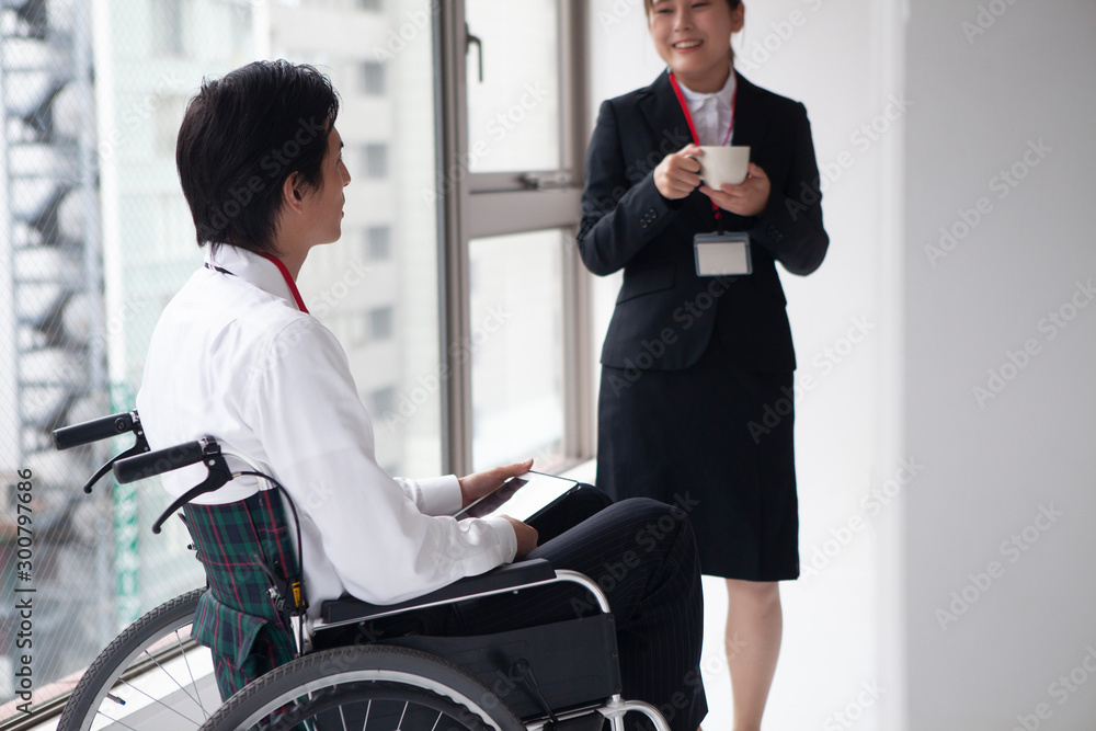 女性社員と談笑する車椅子のビジネスマン