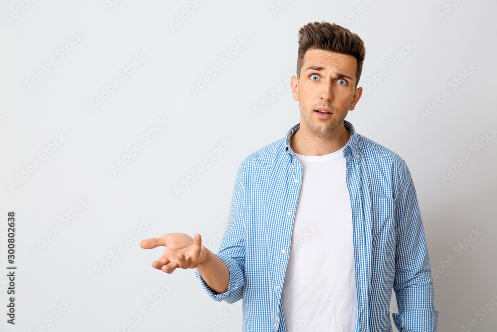 Shocked young man on light background