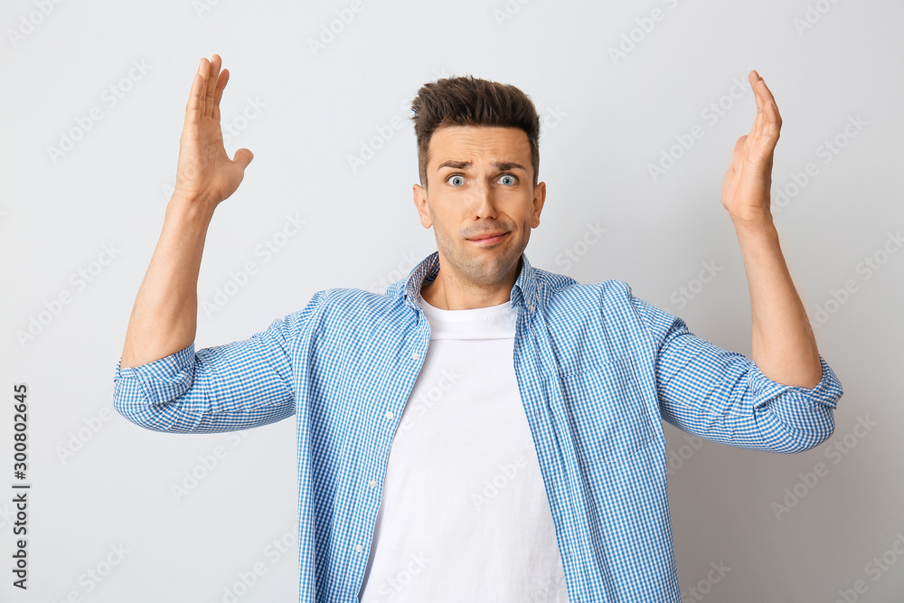 Stressed young man on light background