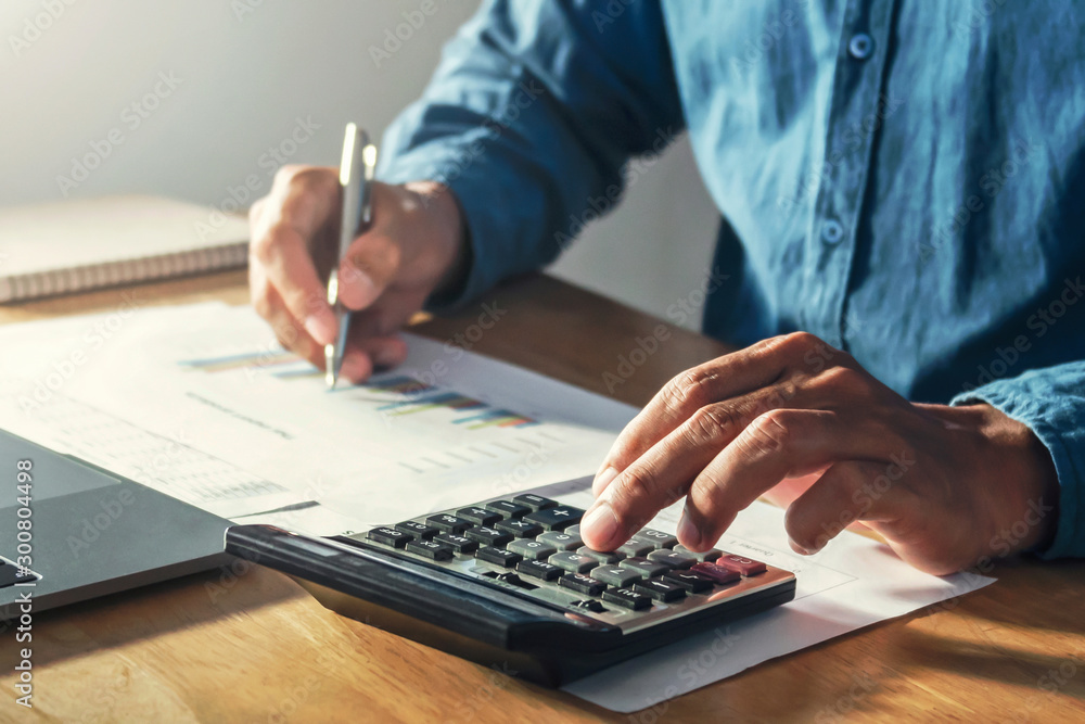 businessman working on desk office with using a calculator to calculate budget, finance concept