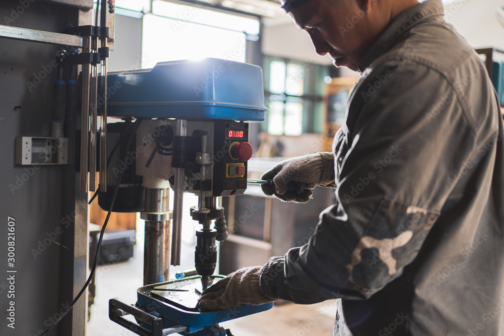 Asian technician skilled,he uses a metal lathe.