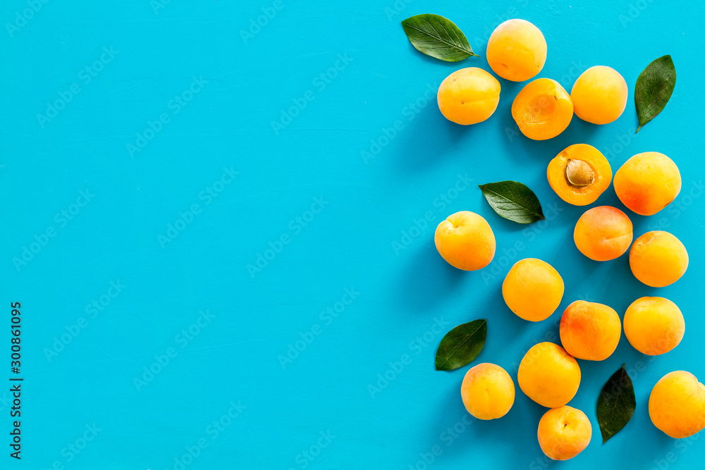 Fruit frame. Apricots and leaves on blue background top view copy space