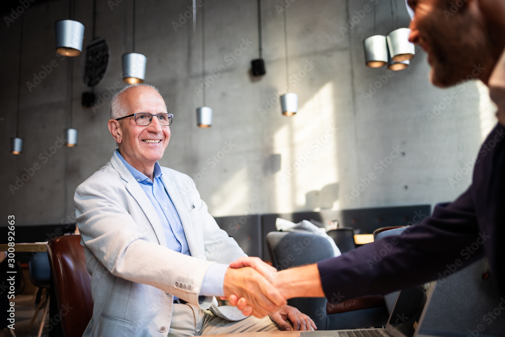 Senior businessman shaking hands during meeting in cafe