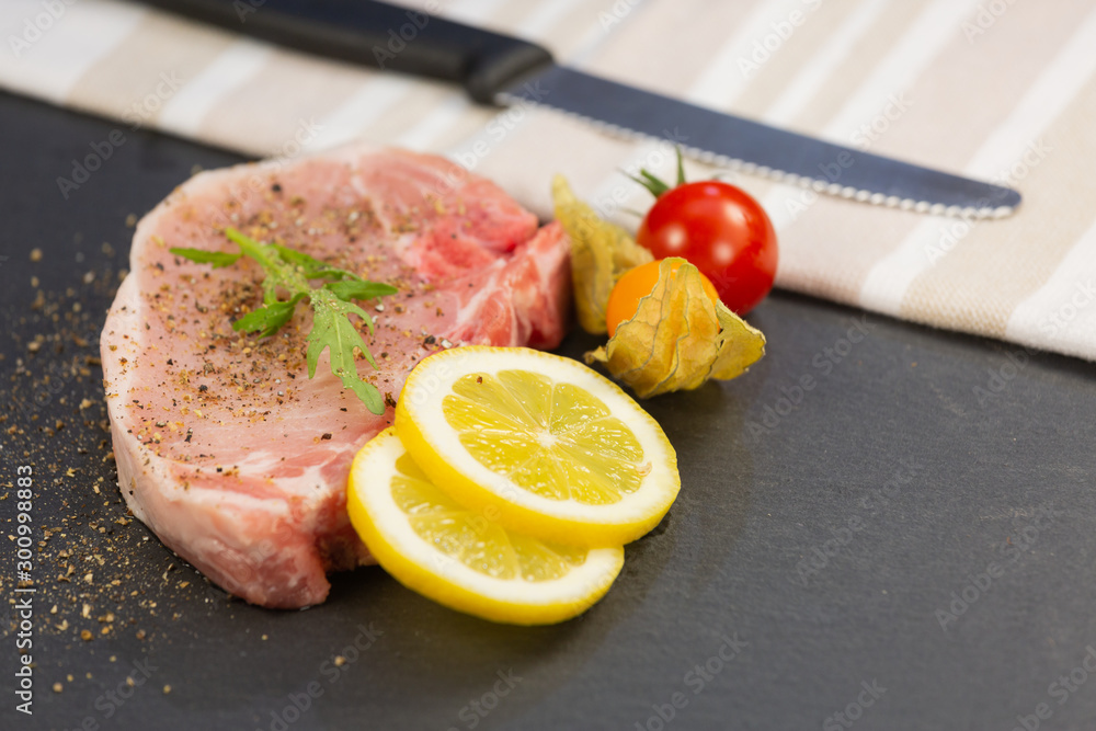  Fresh pork steak with lemon,grapes,tomatoes on Stone tray view.