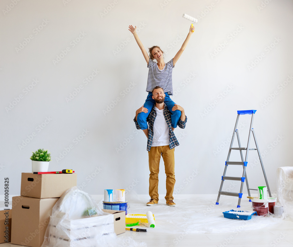 young happy couple is repairing and painting   wall at home.