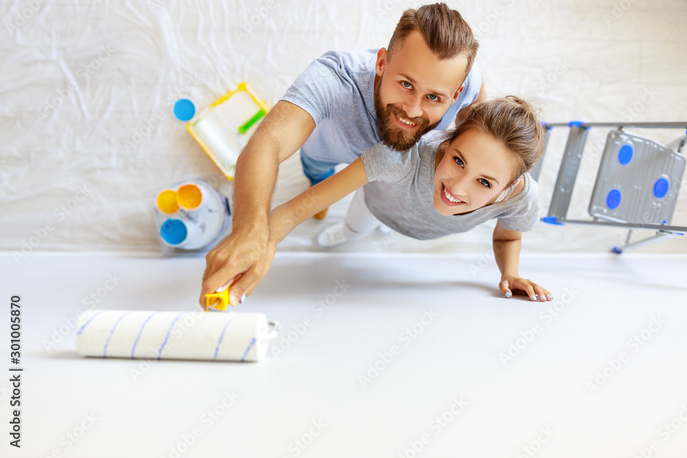 young happy couple is repairing and painting   wall at home