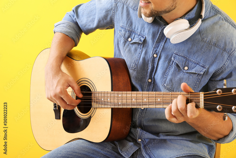 Handsome man playing guitar on color background