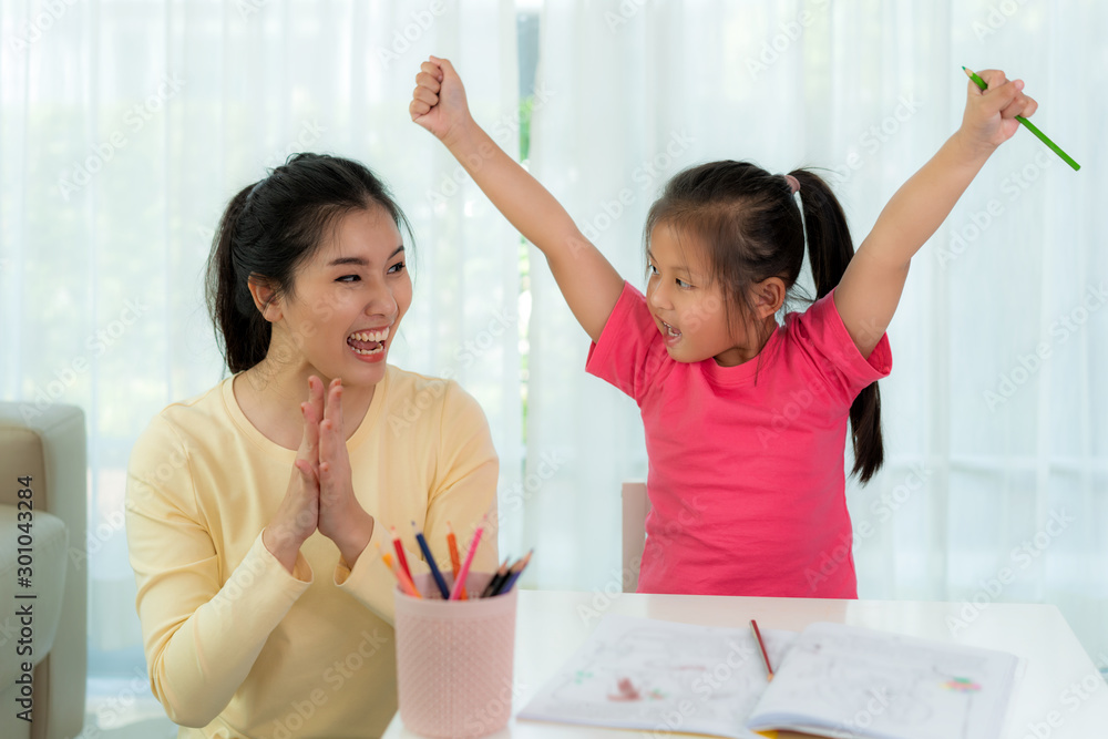 快乐成功的亚洲幼儿园学生和她的母亲举起双手庆祝成功