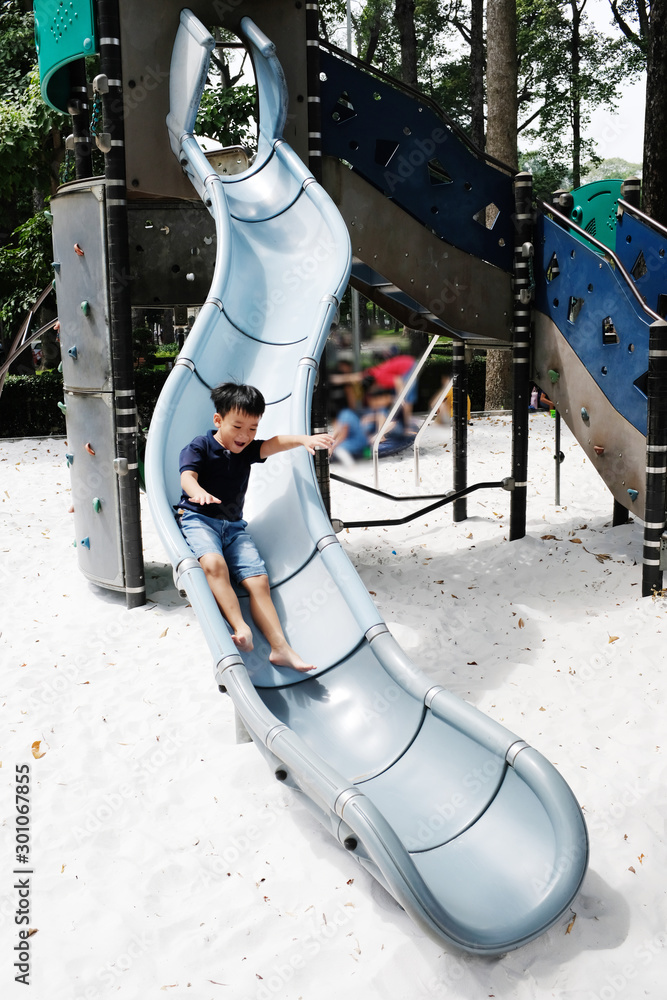 Ho Chi Minh City, Vietnam - October 25, 2017: Active boy sliding down in public playground