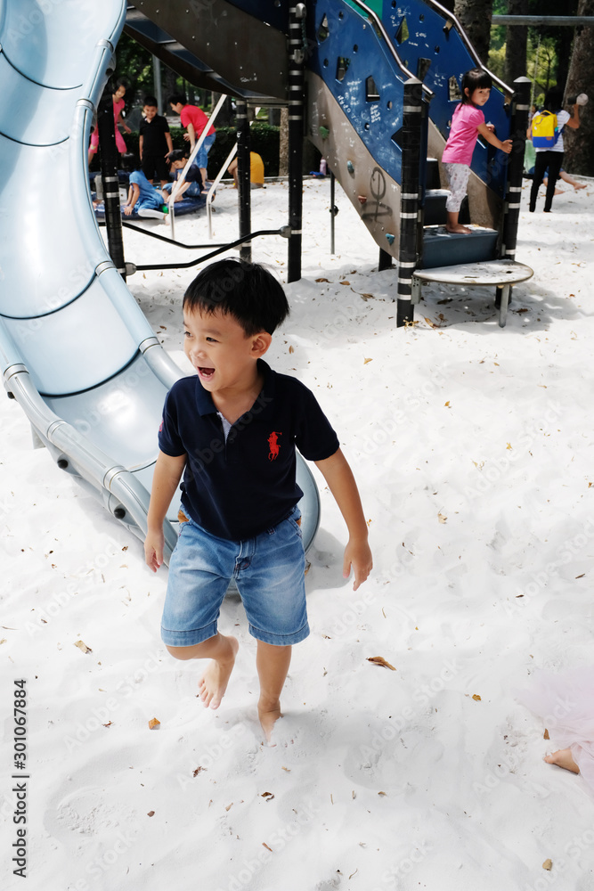 Ho Chi Minh City, Vietnam - October 25, 2017: Active boy sliding down in public playground