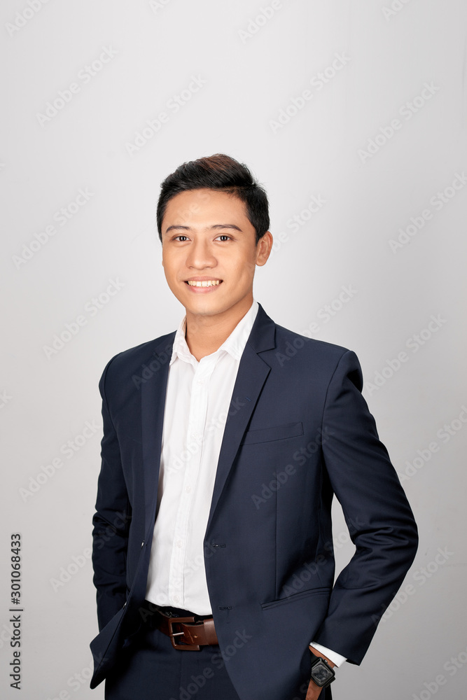 A young Asian man in suit put both hands in his pants pocket, isolated on a white background.