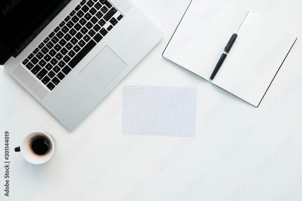 Top view of office table. White office desk table with laptop, cup of coffee and supplies.