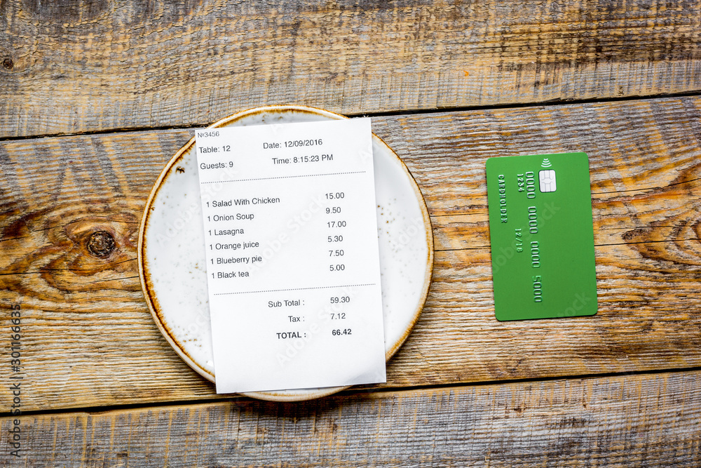 paying check for lunch with card wooden table background top view