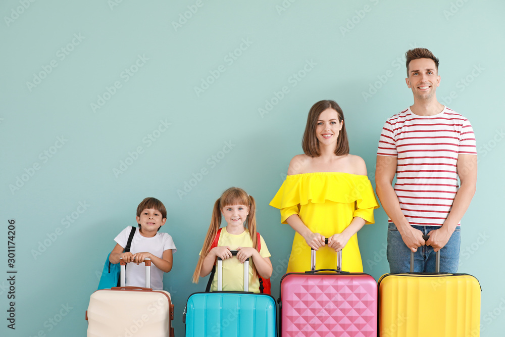 Happy family with luggage on color background