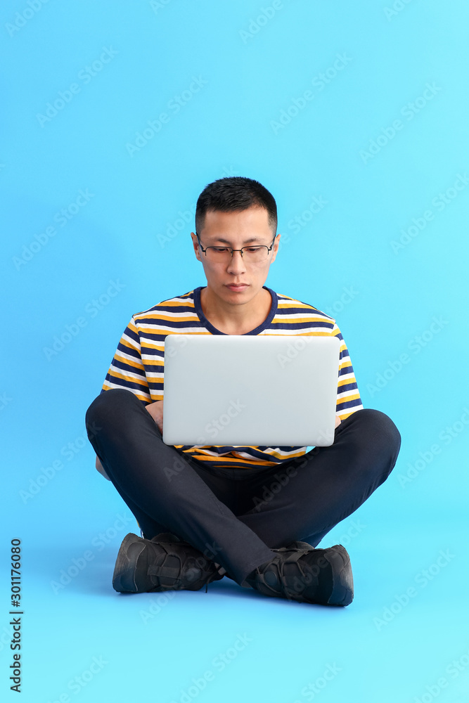 Asian programmer with laptop on color background