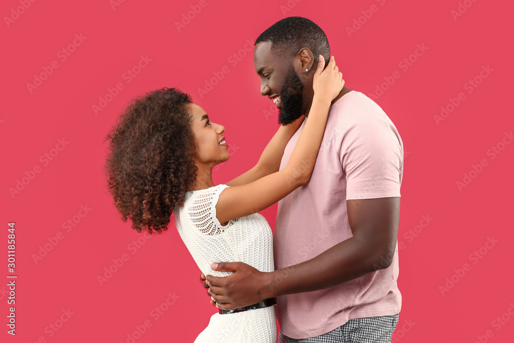 Portrait of happy African-American couple on color background